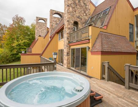 an outdoor hot tub outside a yellow vacation condo in killington vermont