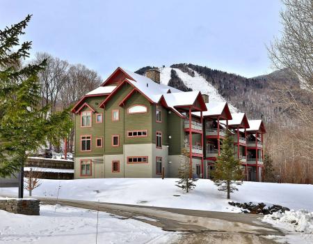 The Lodges at Sunrise - a large brown ski lodge in Killington - sits snow-covered in the wintertime
