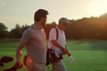 two men walking on golf course at sunset