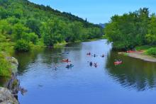 people kayaking and tubing a river in vermont in summer