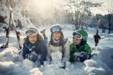 three little boys in the snow with skis beside them