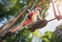 view from bottom of person walking on a ropes course