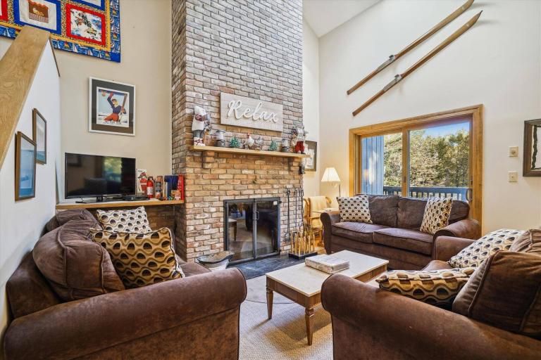 a large living room with seasting for 8 and a large brick fireplace