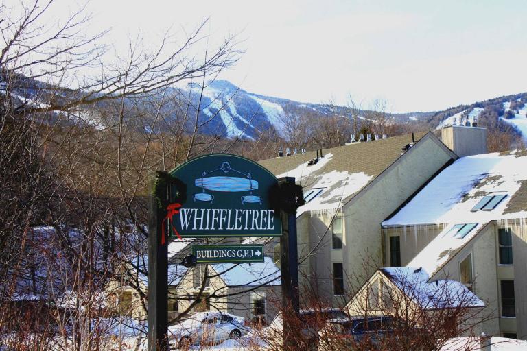 a green sign in front of snowy mountains. the white, italicized text says, "Whiffletree."