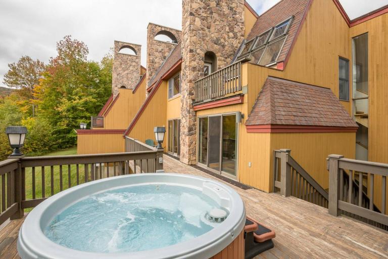 an outdoor hot tub outside a yellow vacation condo in killington vermont