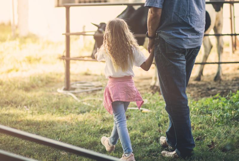 father and daughter walking past farm animals 